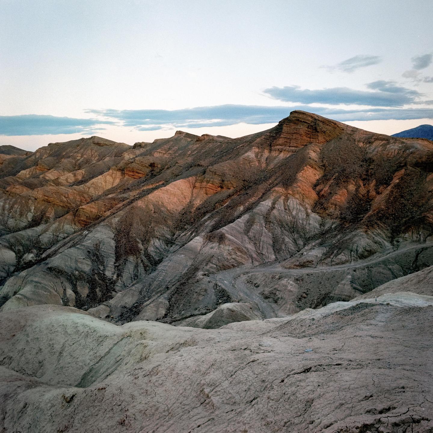 A landscape view shows rugged, colorful mountains under a cloudy sky.