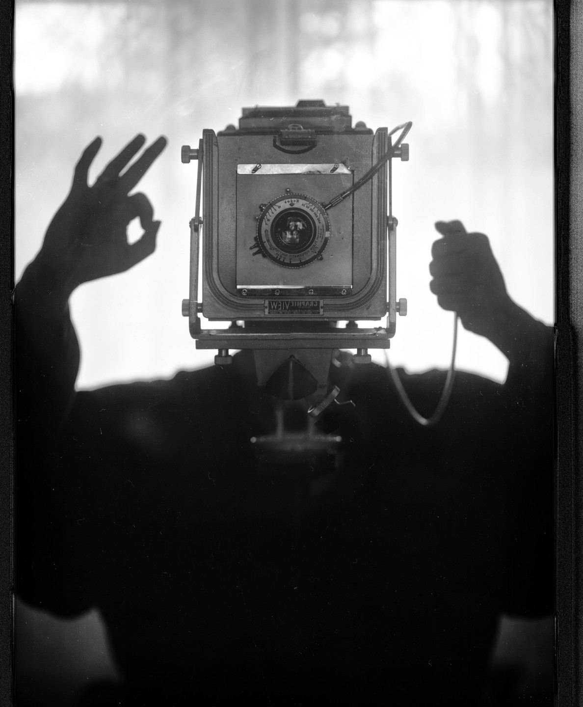 A self-portrait shows a camera with the photographer's hands making an "ok" sign and holding a cable release.