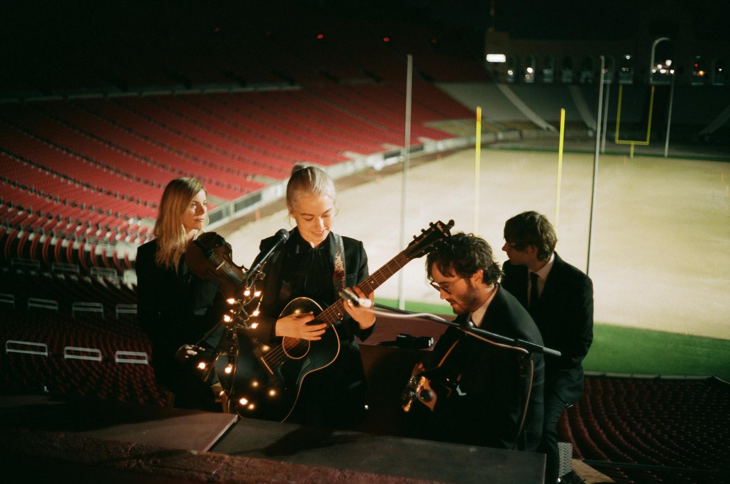 A band performs on a stage in a stadium at night.