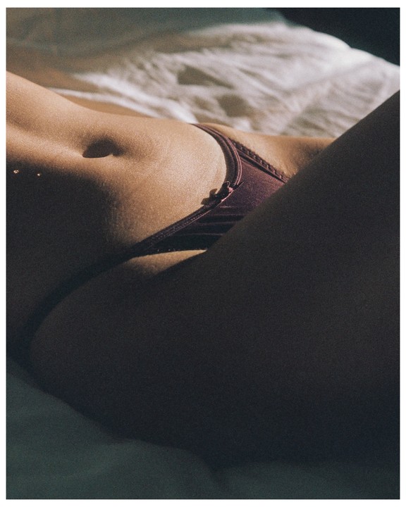 A woman's torso is visible, with her midriff and upper thighs in focus, wearing purple underwear.