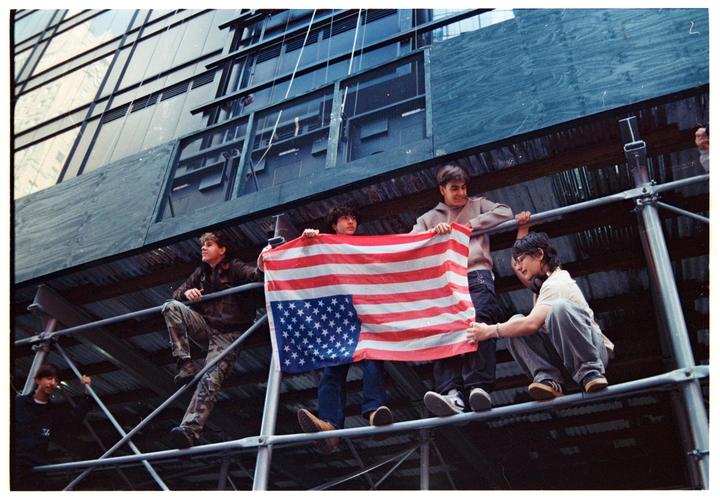 Several young men are gathered on scaffolding, holding an American flag.