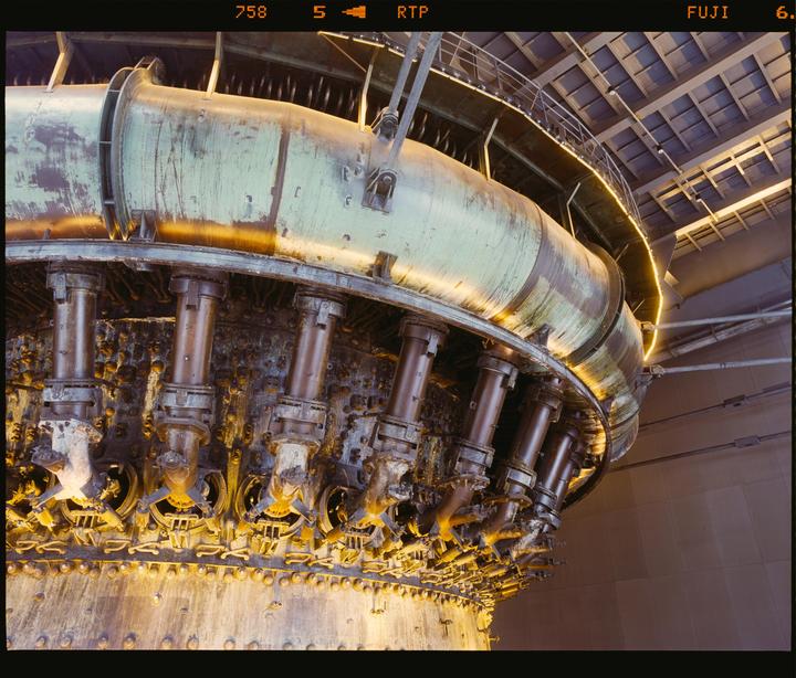 A large industrial furnace with pipes and metal structures is illuminated by warm light.