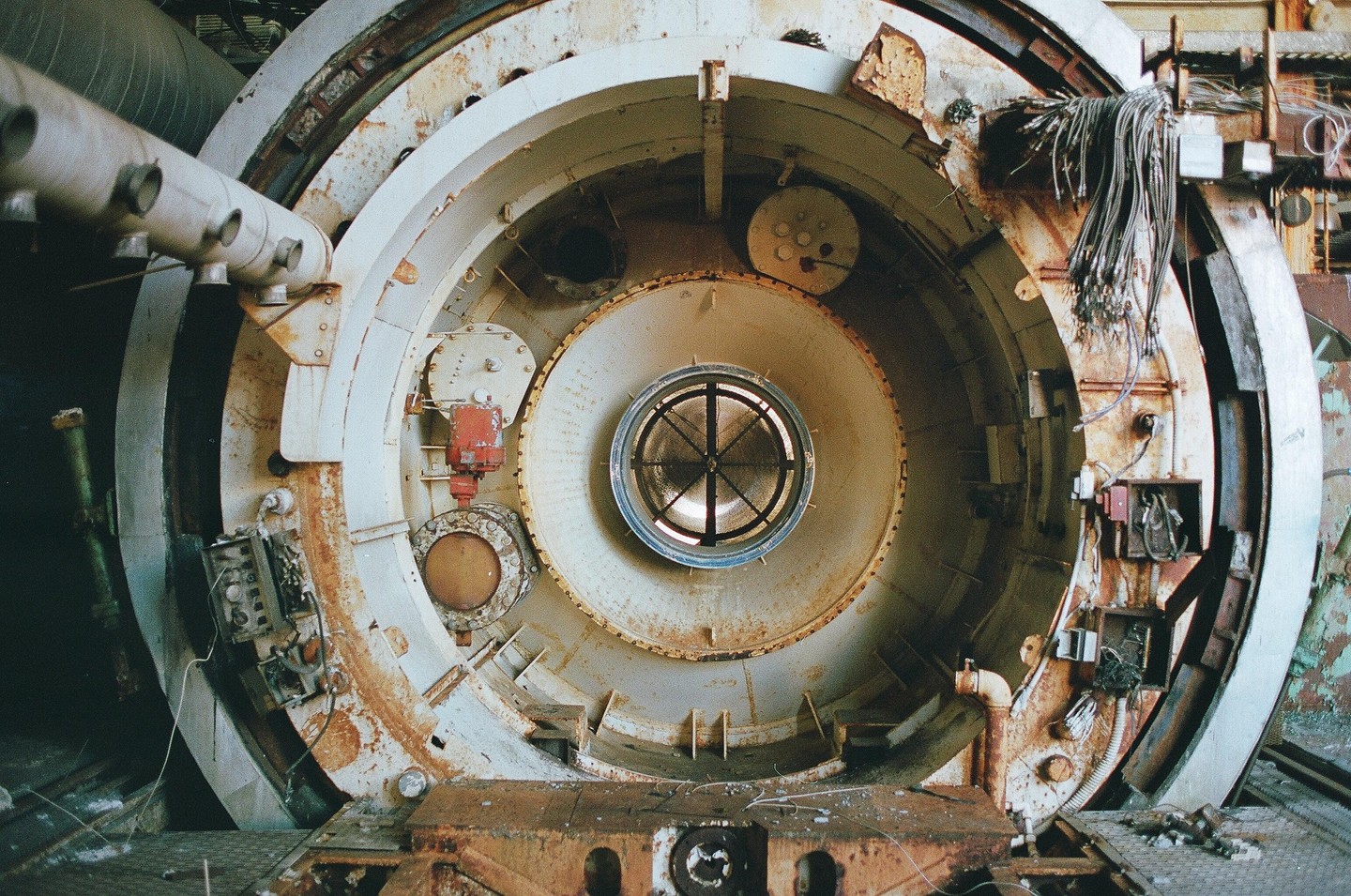 A large, circular, rusty industrial machine with a central grate is shown in a close-up.