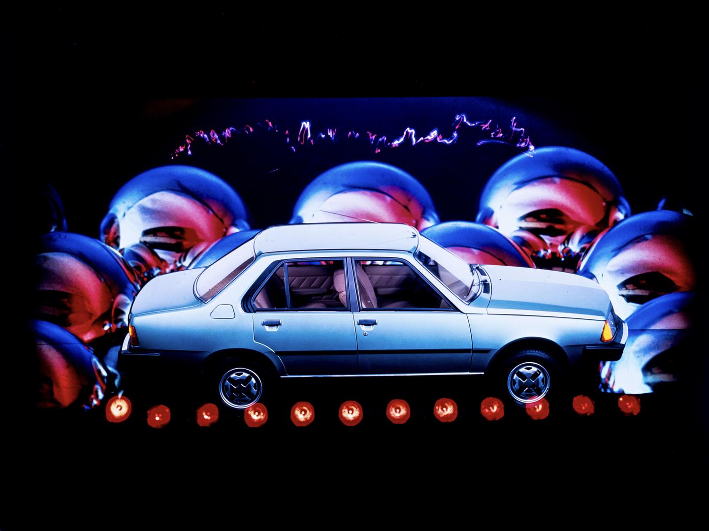 A light blue car is surrounded by large, shiny, colorful spheres and small orange lights.