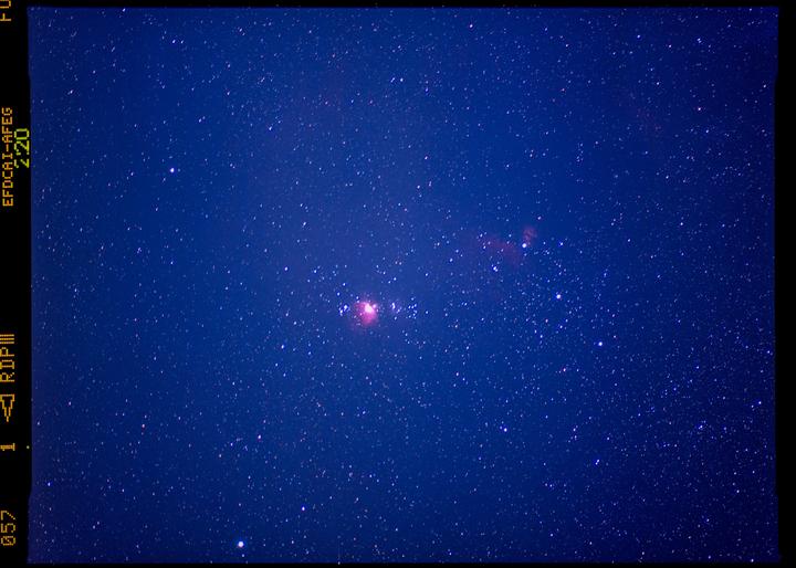 The Orion Nebula is visible in a dark blue night sky filled with stars.