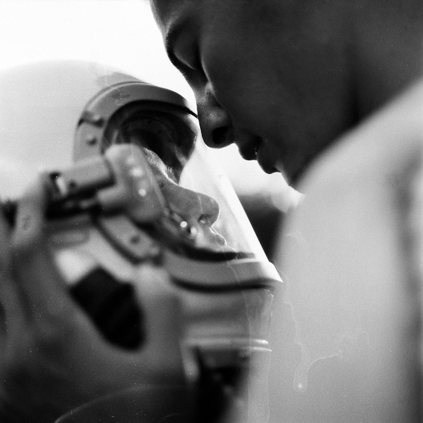 A person's face is visible in profile, looking down at a helmet.