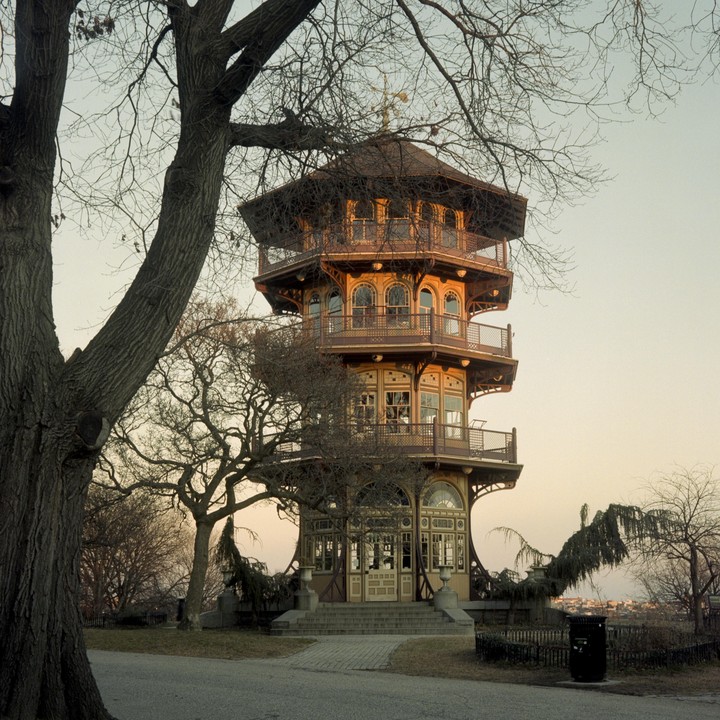 A pagoda stands tall with multiple levels and balconies, framed by the bare branches of a large tree in the foreground.