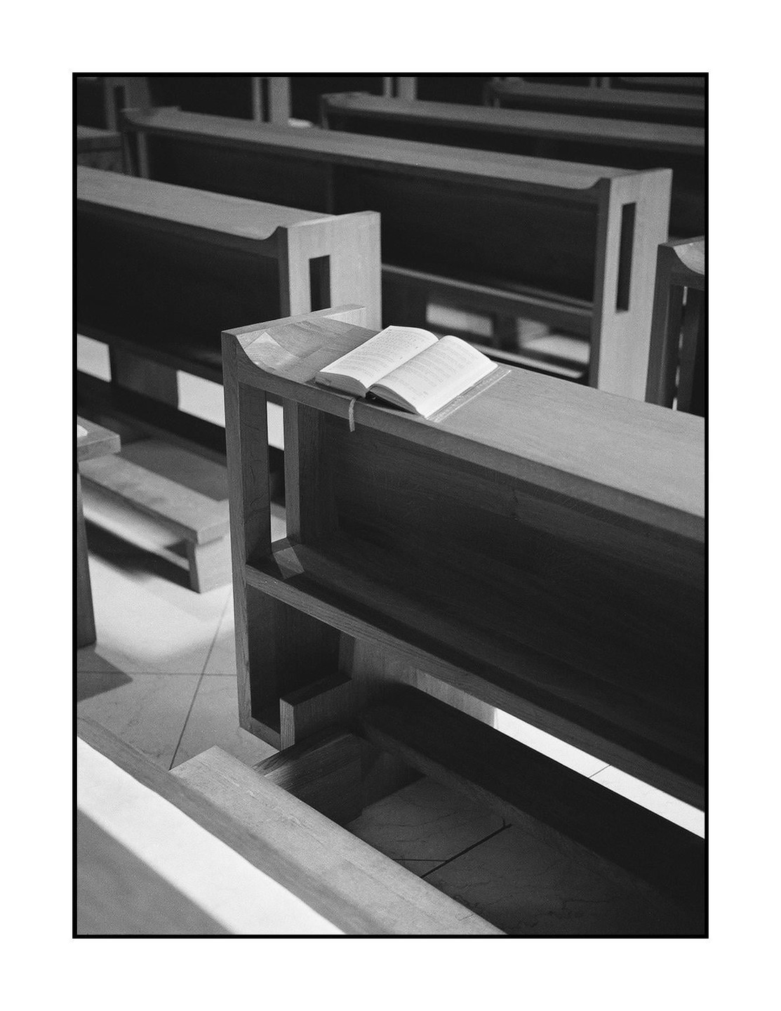 An open book rests on a wooden pew in a church.
