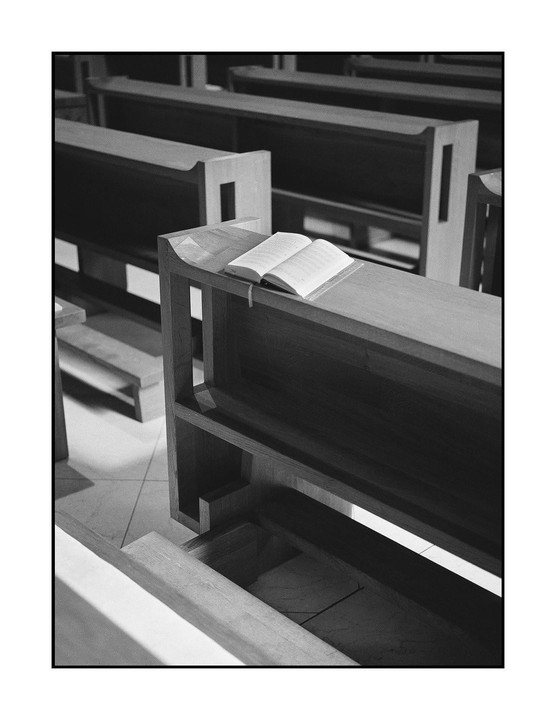 An open book rests on a wooden pew in a church.