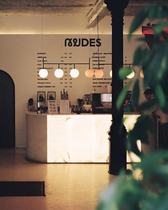 A cafe counter with a menu board and a person standing behind it.