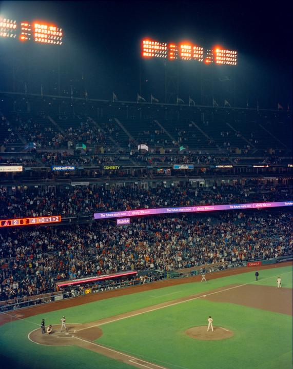 A baseball game is played at night in a stadium full of spectators.