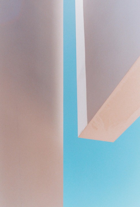 A minimalist composition features intersecting planes of blue, beige, and white.