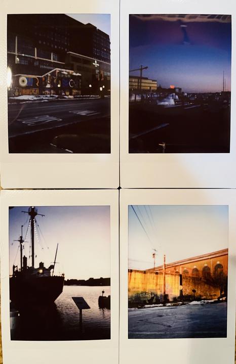 Four instant photos show different views of Baltimore, including a street with a building and a boat on the water.