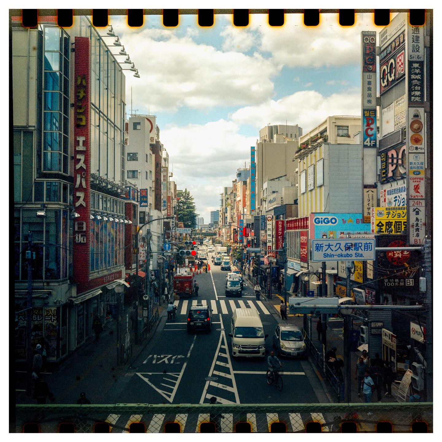 A busy street in Tokyo is filled with cars, pedestrians, and buildings with many signs.