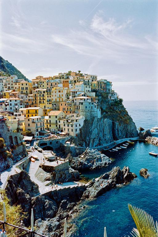 A village with colorful buildings is built into a cliff overlooking the sea.