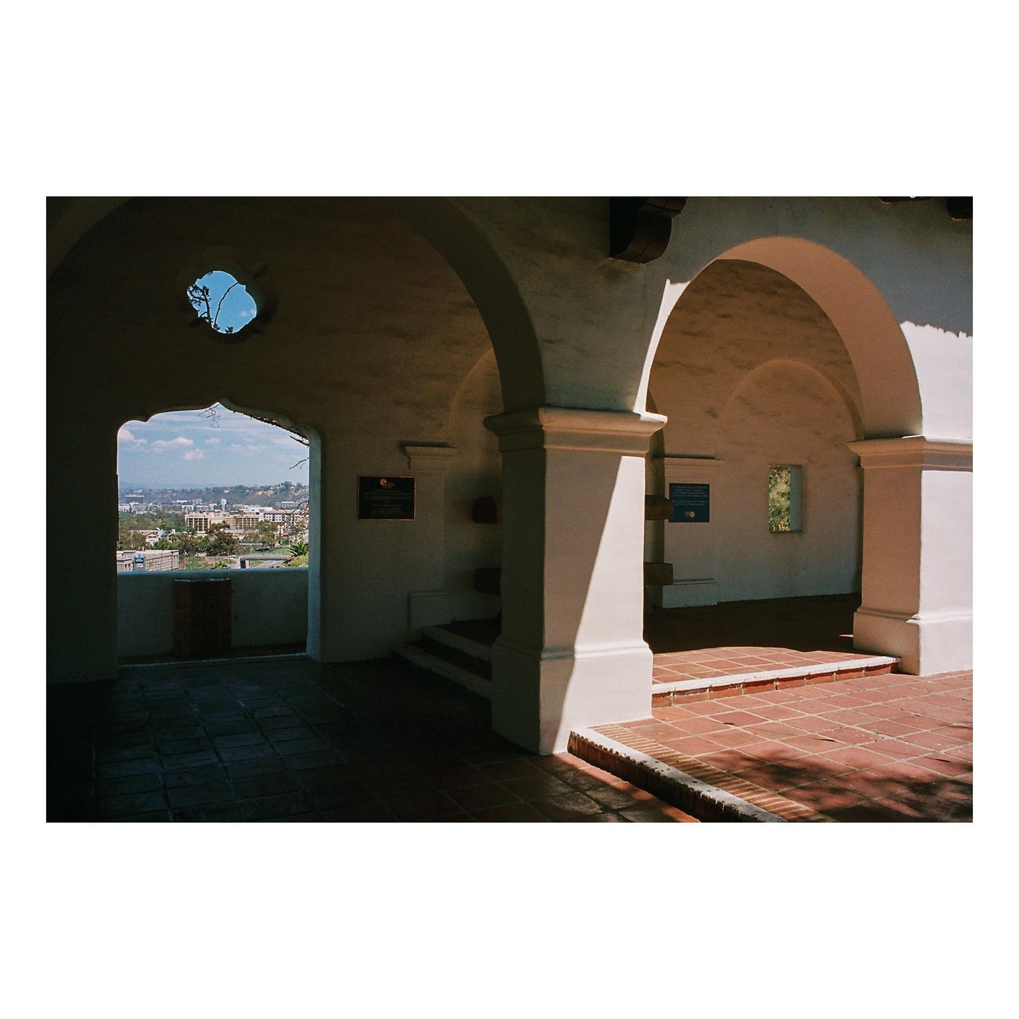 A view of a city from an arched walkway with a tiled floor.
