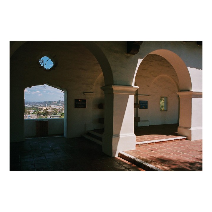 A view of a city from an arched walkway with a tiled floor.