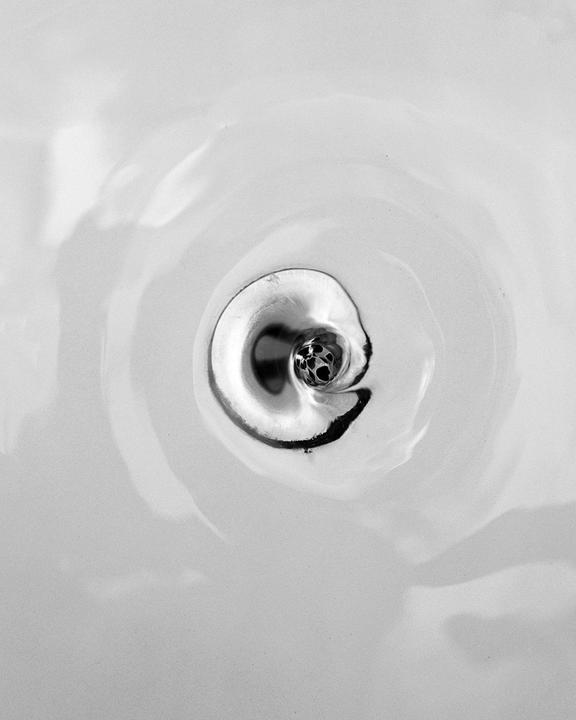 Water swirls around a drain in a sink.