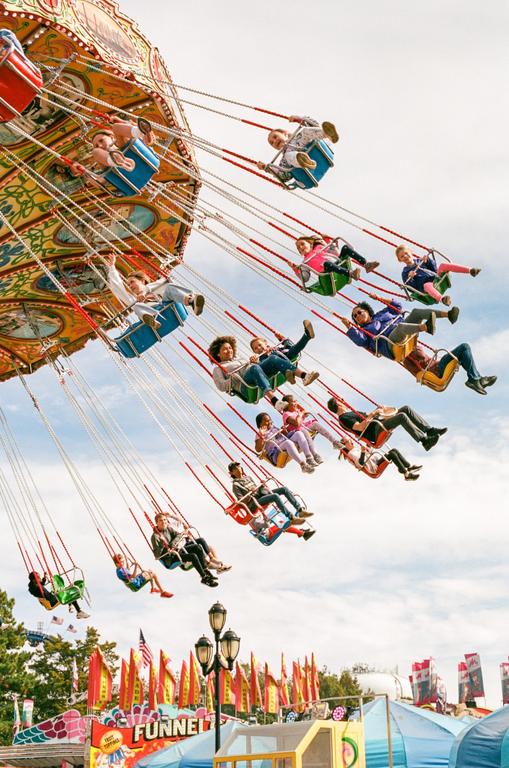 People of all ages are riding a swing ride at a carnival.