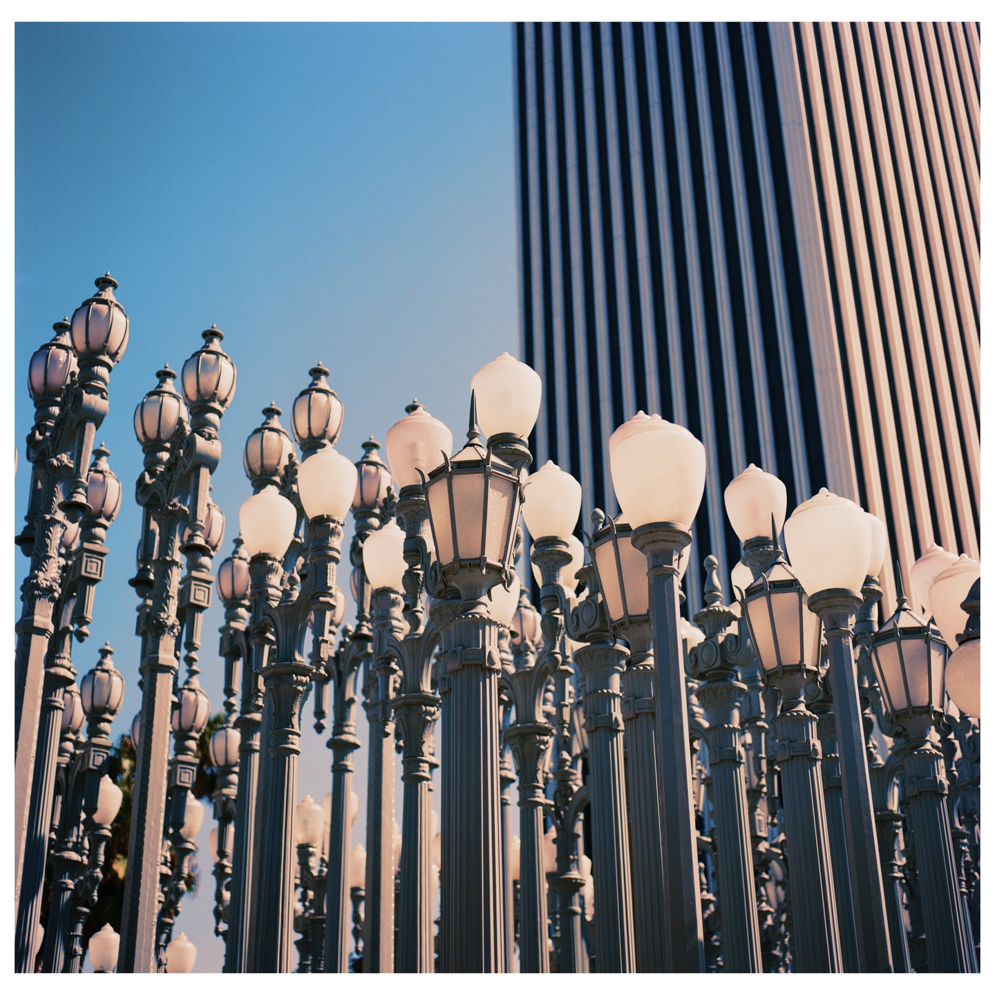 A collection of street lamps stands in front of a tall building with vertical stripes.