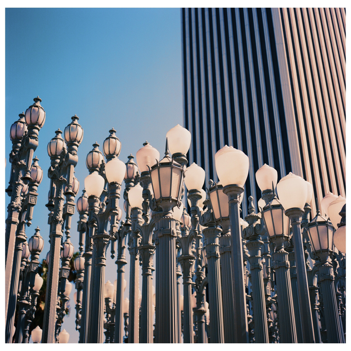 A collection of street lamps stands in front of a tall building with vertical stripes.