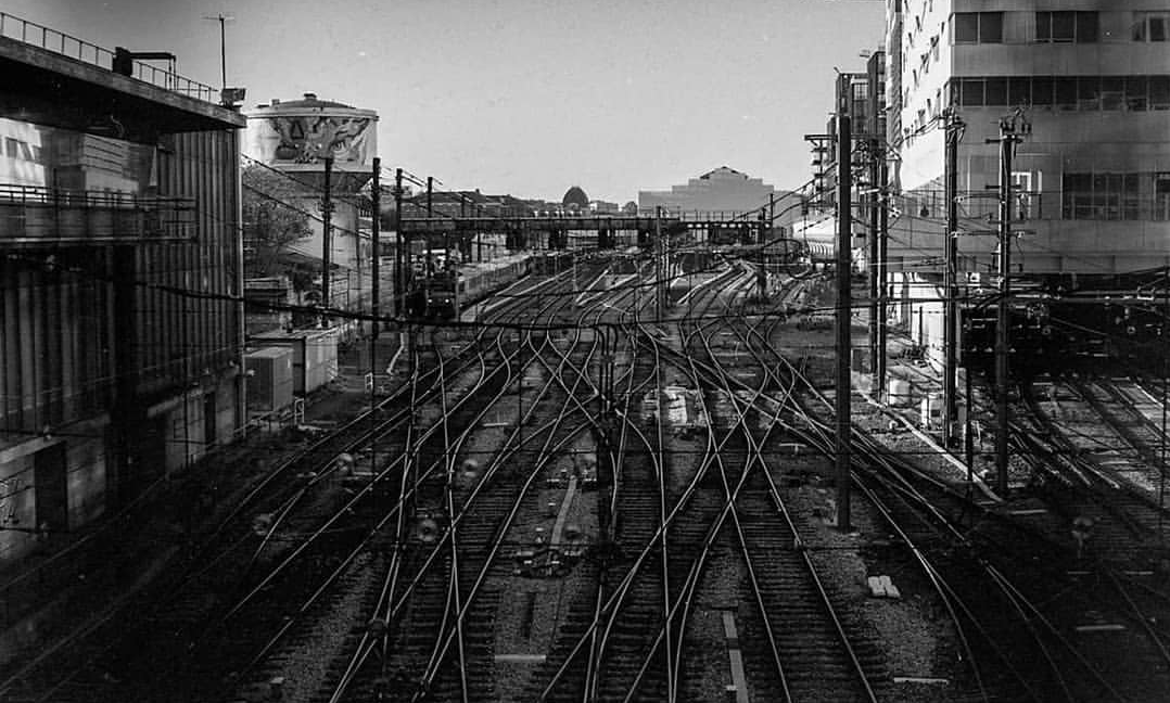 A complex network of railway tracks leads to a train station with buildings on either side.