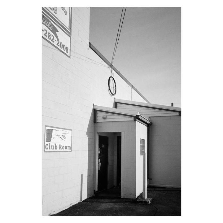 A black and white photograph shows the entrance to a "Club Room" with a sign pointing towards it.