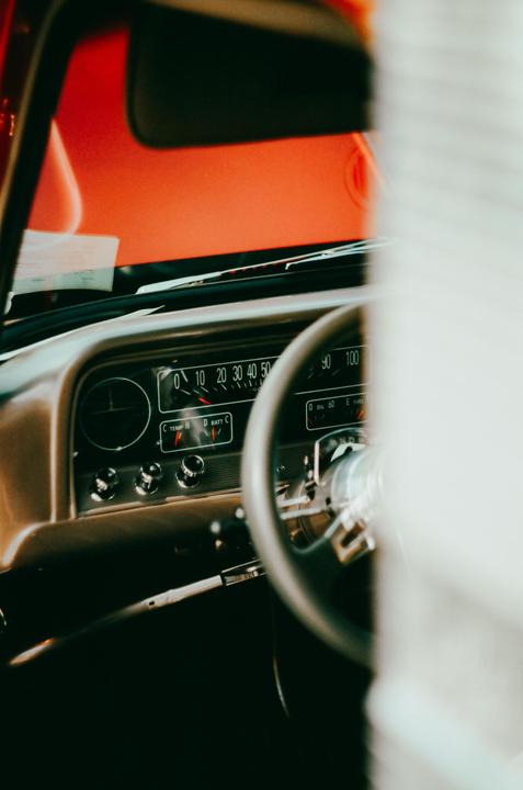 The dashboard and steering wheel of a vintage car are visible from the passenger side.