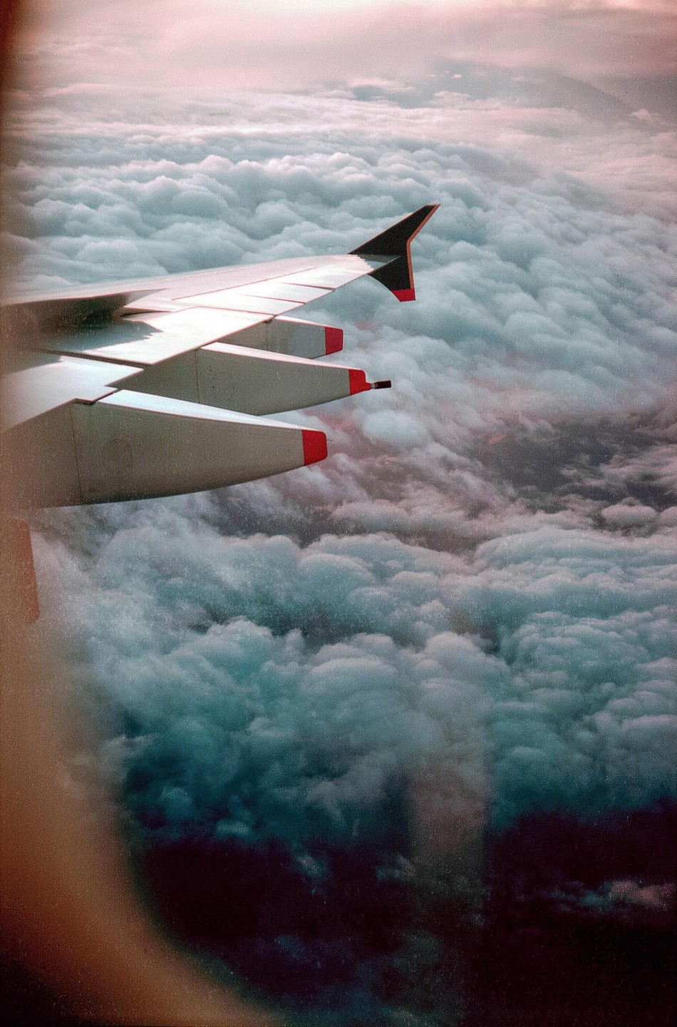 An airplane wing is visible above a vast expanse of clouds.