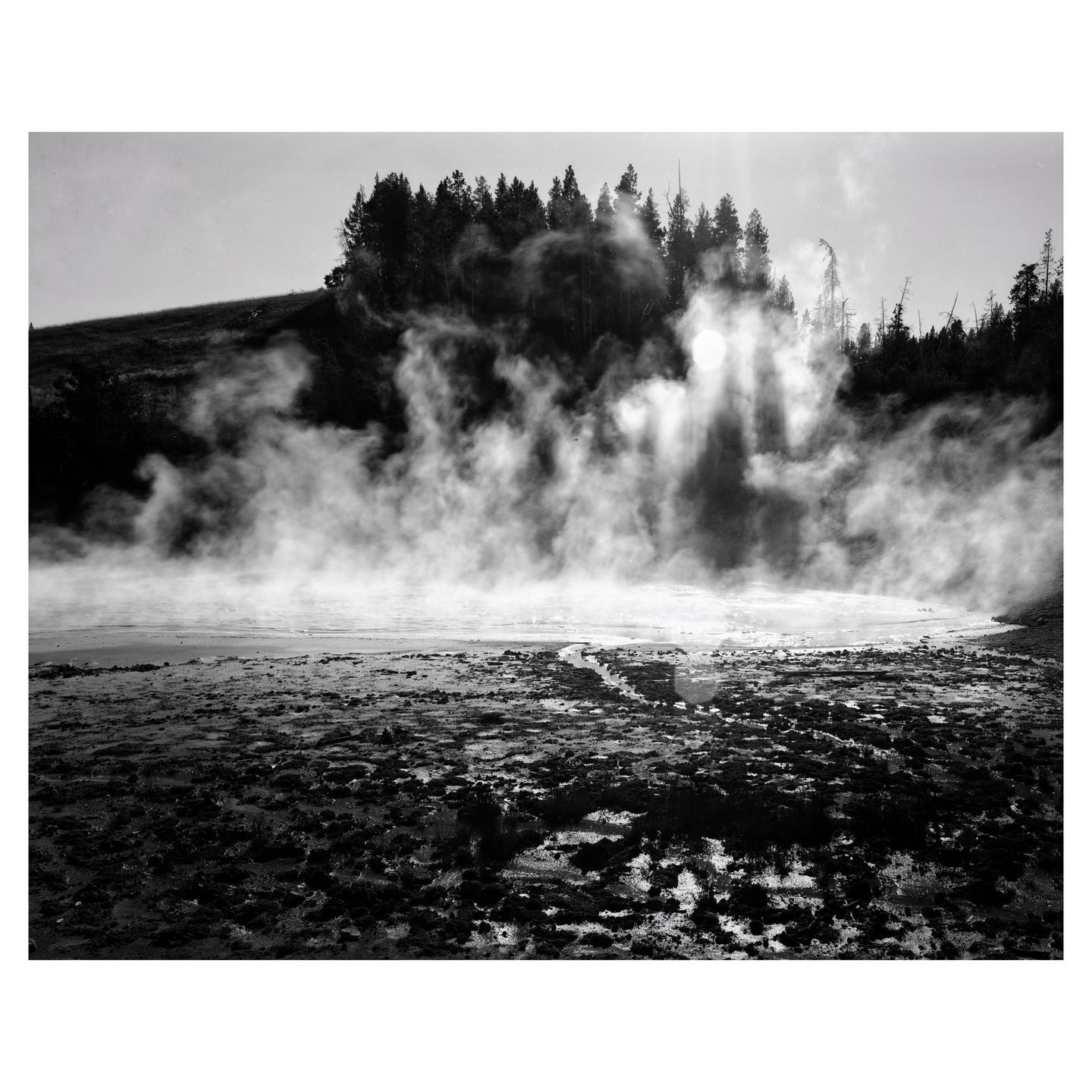 Steam rises from a muddy landscape with a forest in the background.