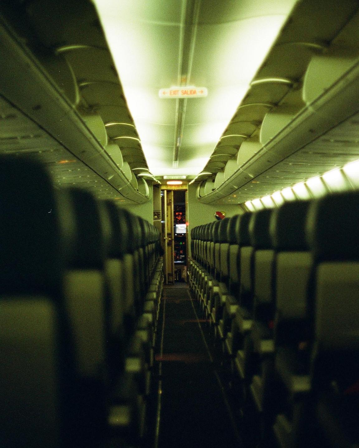 An empty airplane cabin is visible from the back, looking towards the cockpit.