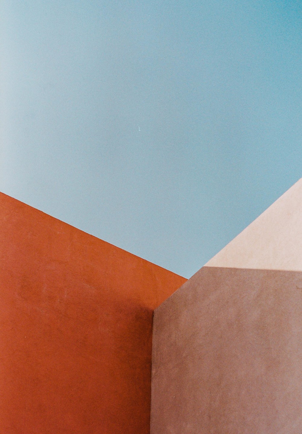 A minimalist composition features geometric shapes in blue, orange, and brown with shadows.