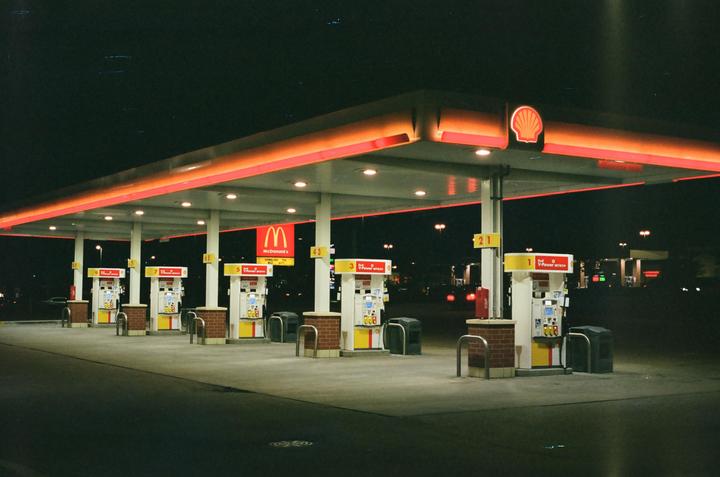 A gas station with a Shell logo and a McDonald's sign is illuminated at night.