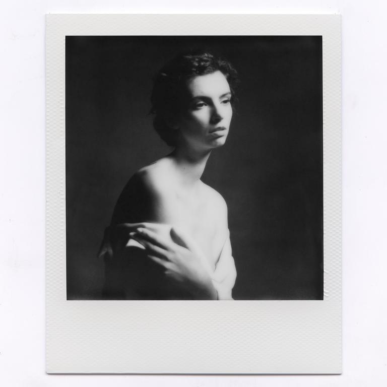 A woman with bare shoulders looks away from the camera in a black and white portrait.