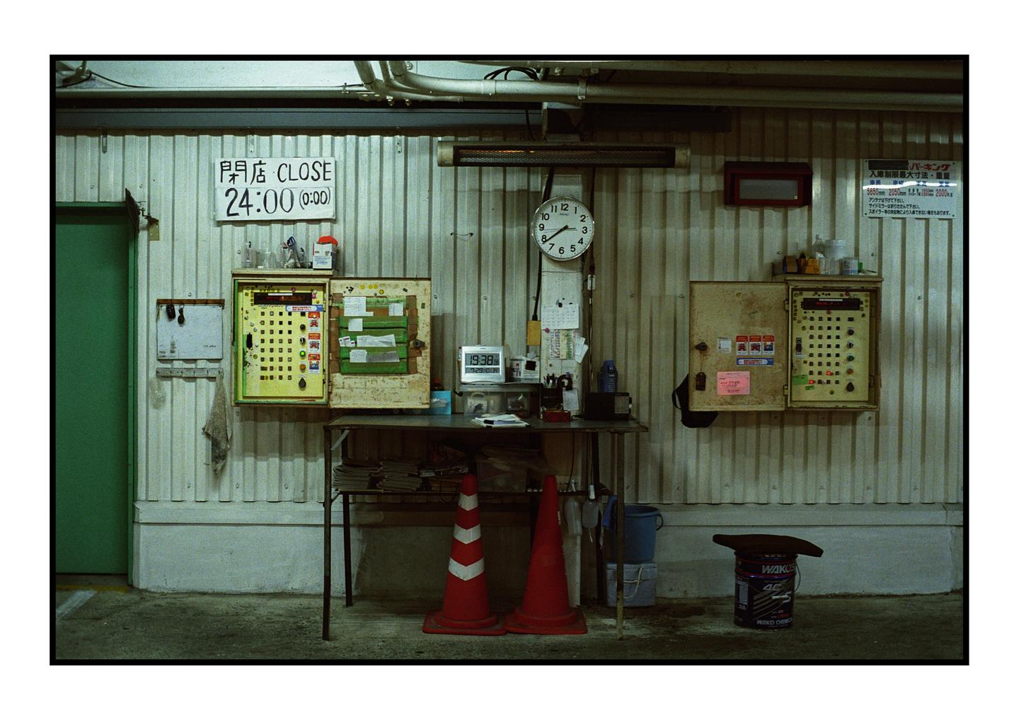 A cluttered work area with a table, two traffic cones, and various items on a corrugated metal wall.