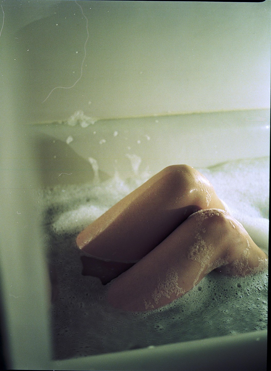 A person's legs are visible in a bubble bath.