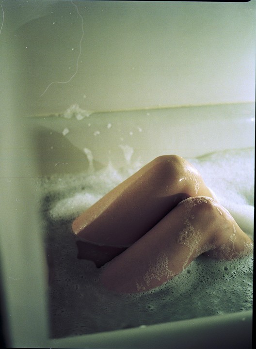 A person's legs are visible in a bubble bath.