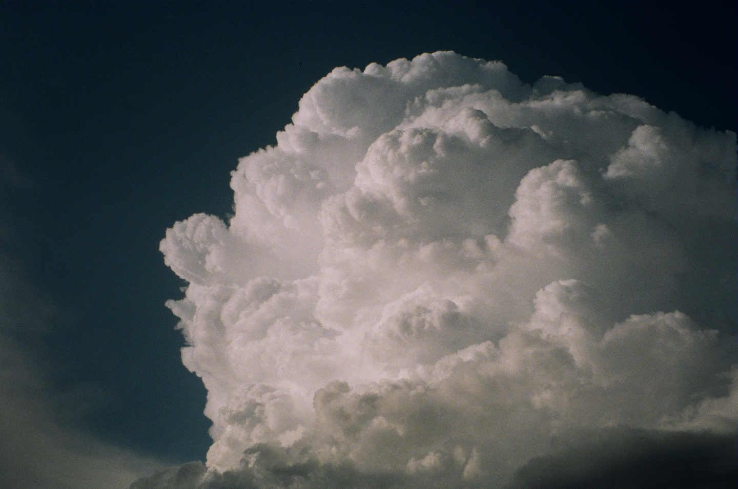 A large, fluffy cumulus cloud fills most of the frame against a dark blue sky.