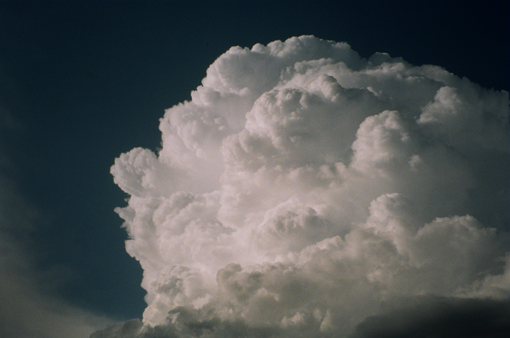 A large, fluffy cumulus cloud fills most of the frame against a dark blue sky.