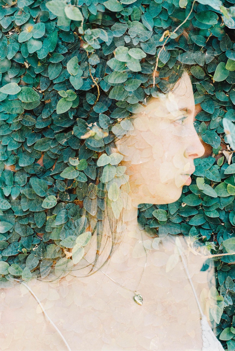 A woman's profile is visible through a double exposure with green leaves.