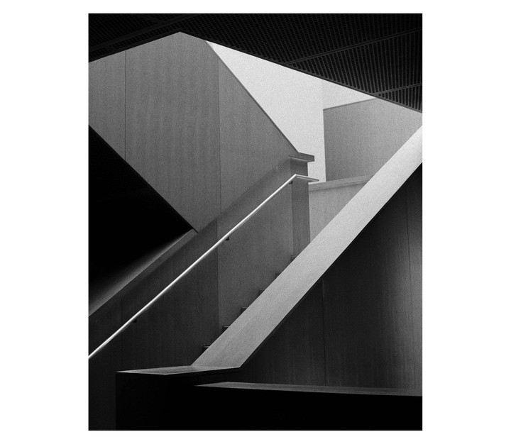 A black and white architectural abstract shows a staircase with railings and geometric shapes.