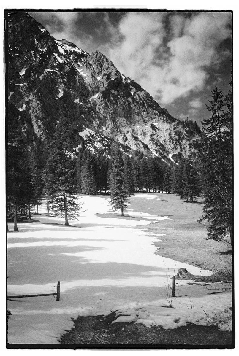 A snow-covered field with trees and a mountain in the background is visible under a cloudy sky.