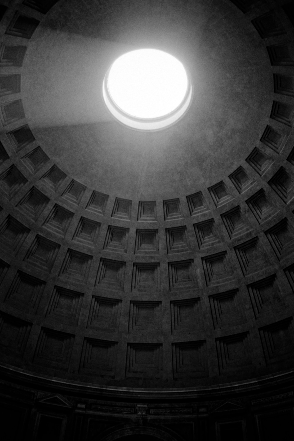 A beam of light shines through the oculus of the Pantheon, illuminating the coffered dome.