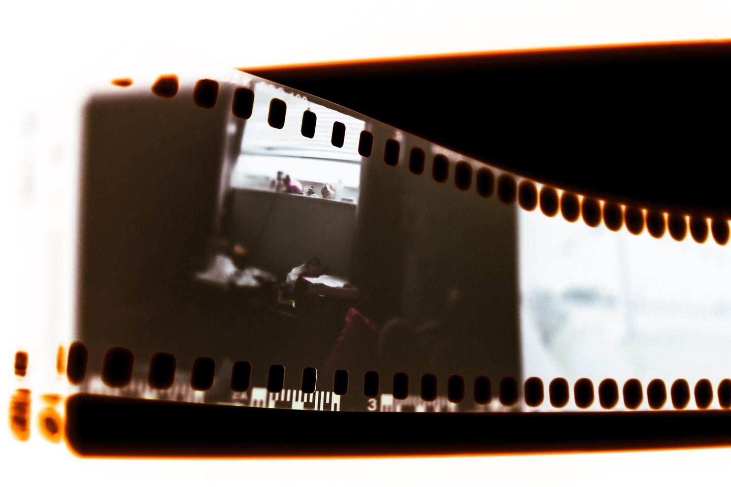 A strip of film shows a blurry image of an interior space with a window.