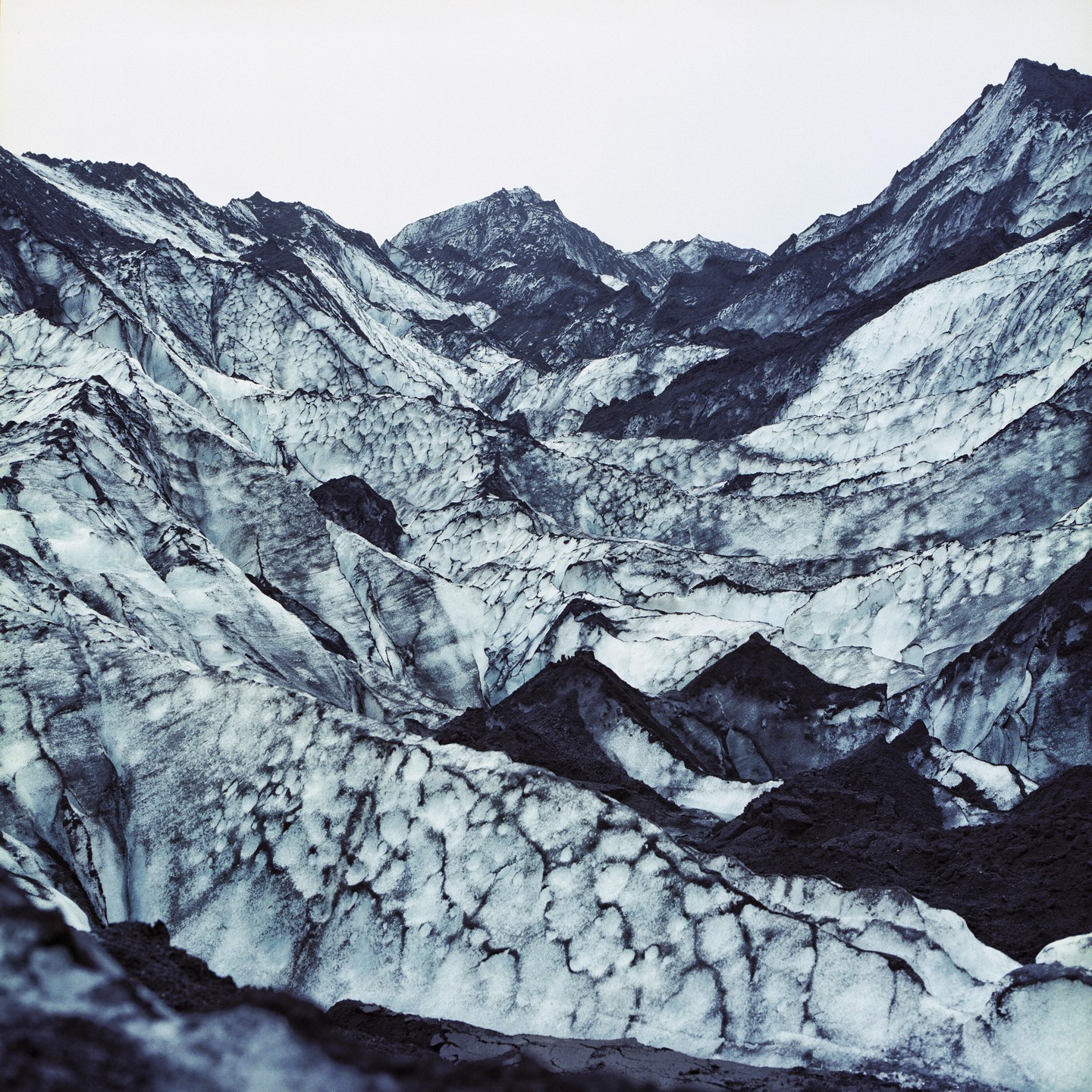 A glacier with dark rock formations is visible under a bright sky.