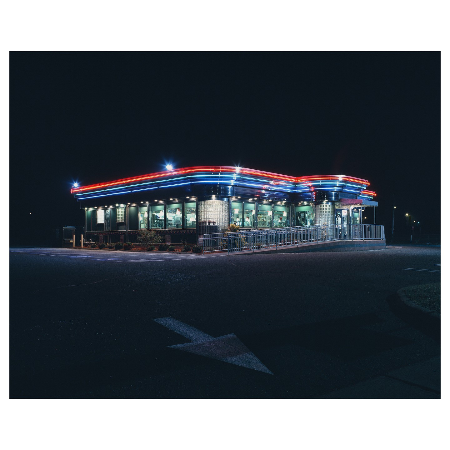 A diner with neon lights is illuminated at night.