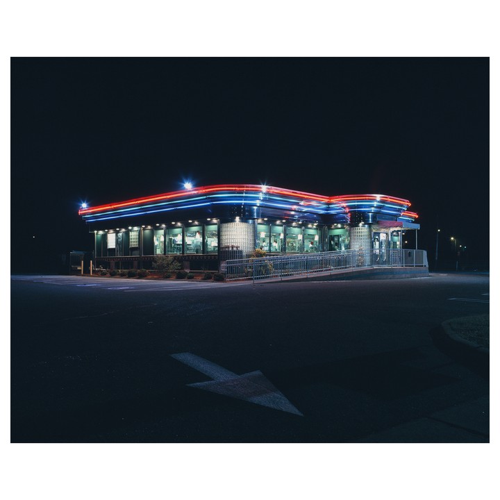 A diner with neon lights is illuminated at night.
