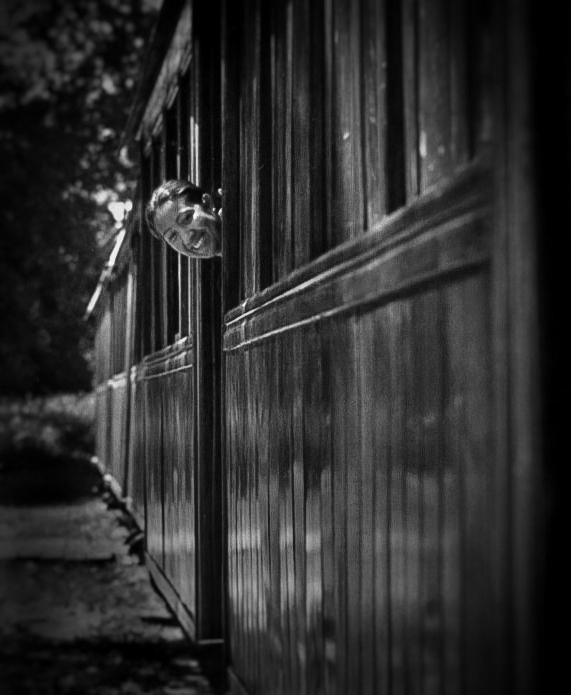 A smiling child looks out from a train window.