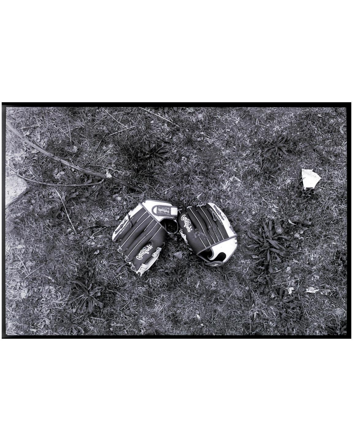 Two baseball gloves are lying on a patch of grass.