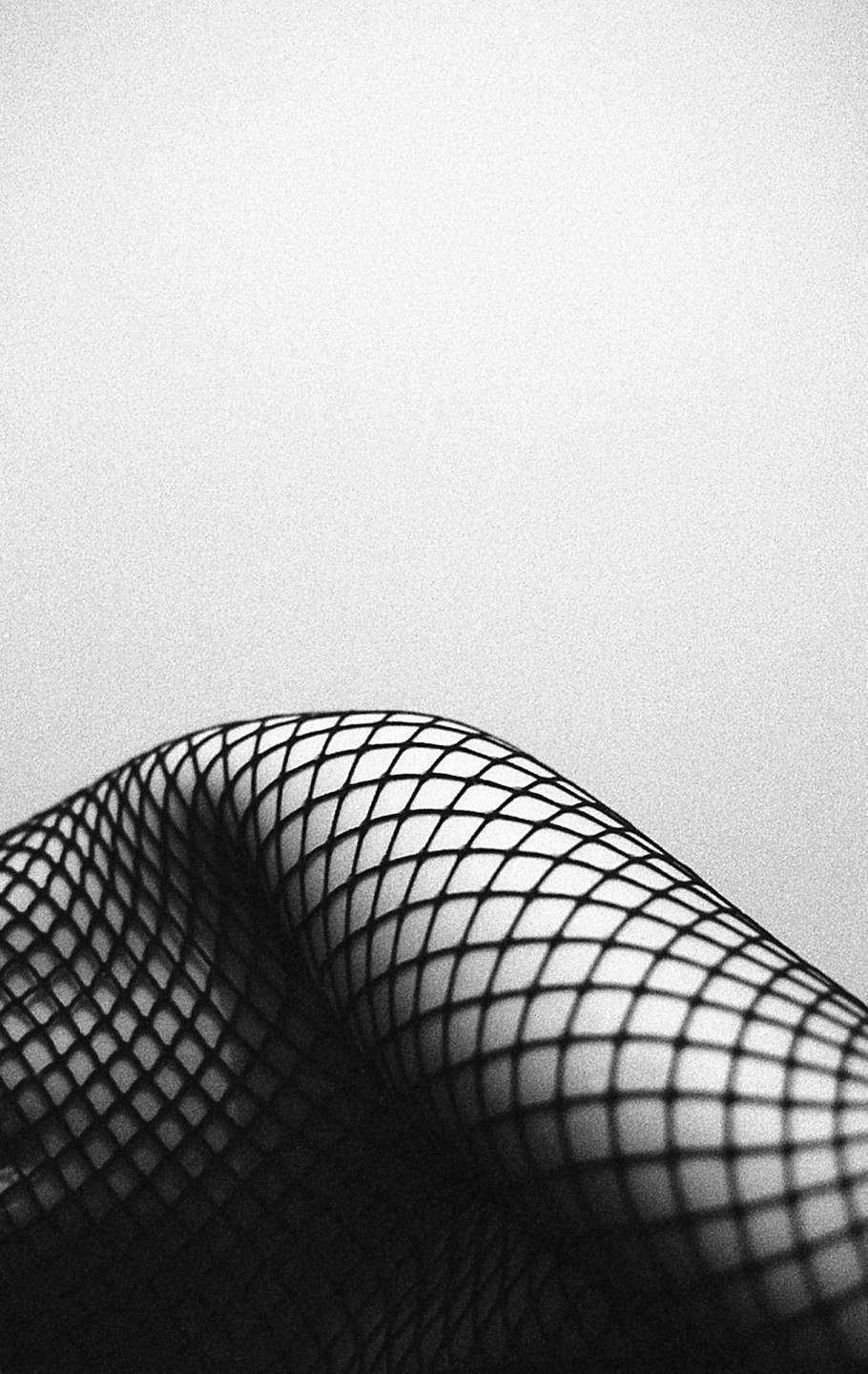A person's legs are covered in fishnet stockings.